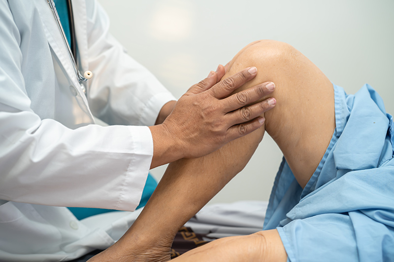 A sports surgeon from Singapore examining a patient’s knee